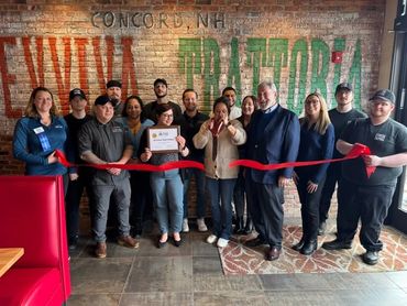 Group of people celebrating a ribbon-cutting event inside a restaurant.
