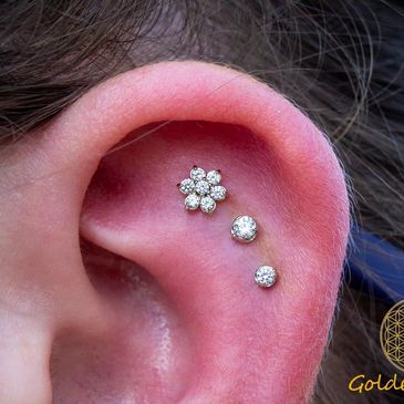 Close-up of an ear with three diamond earrings.