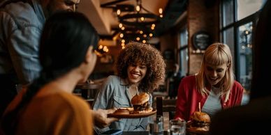 Friends enjoying burgers in a cozy restaurant with warm lighting.