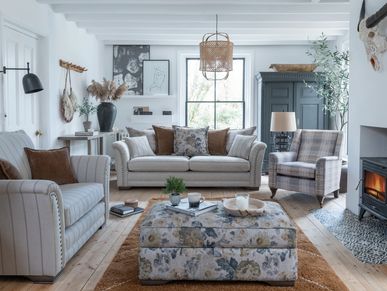Cozy living room with floral ottoman and fireplace.