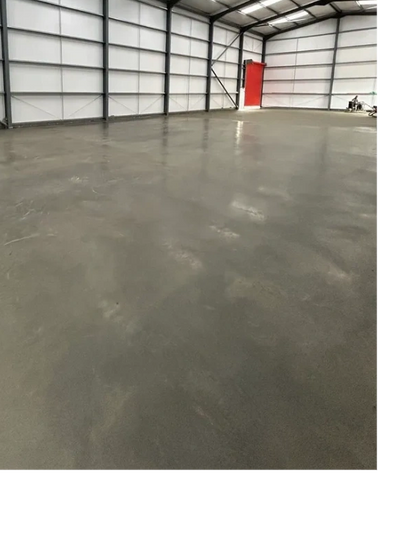 Empty industrial warehouse with polished concrete floor and metal framework.