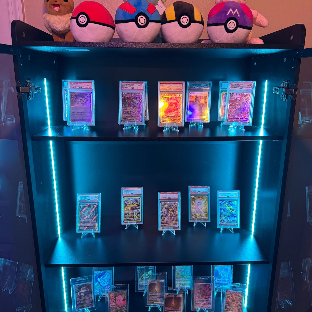 TCG card cabinet with blue LED lights and Pokémon plushies — a collector's dream setup. 