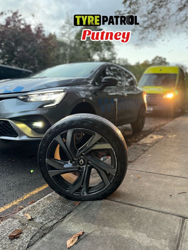 A closup look at a tyre with a car in the back