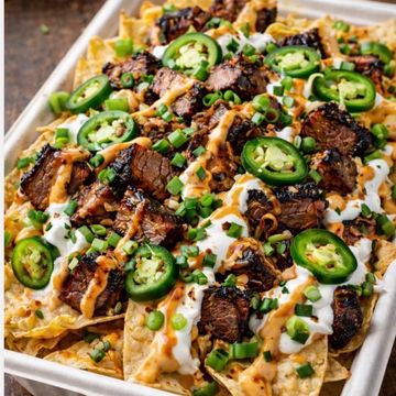 Loaded nachos with grilled steak, jalapeños, sour cream, and green onions.