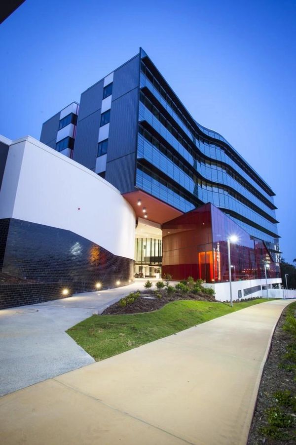 Modern multi-story building with glass and curved facade under a clear blue sky.