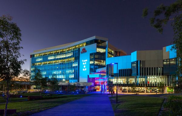 Modern hospital building illuminated at night with blue lights.