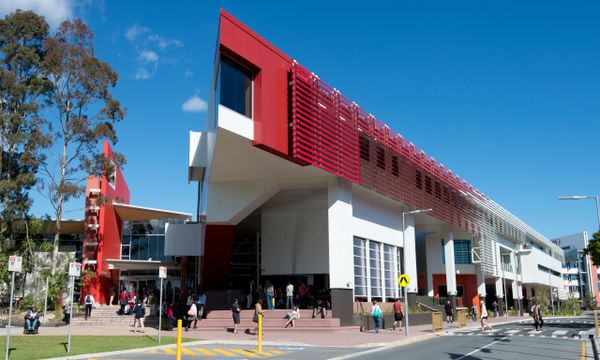 Modern university building with students walking outside on a sunny day.