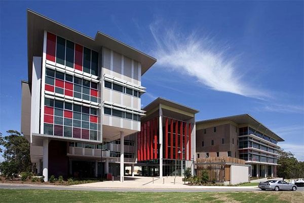 Modern academic buildings with red and gray paneling under a blue sky.