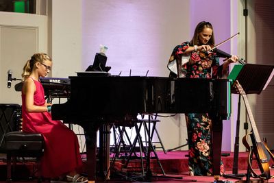 A pianist and violinist perform on stage during a concert.