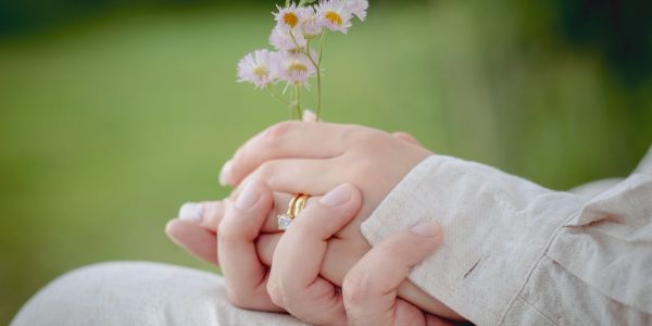 Close-up of hands holding flowers and each other.