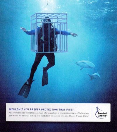 scuba diver partially inside a protective dive cage that is too small to fit diver, sharks circling.