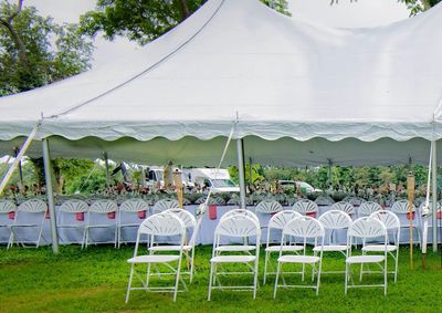 White folding chairs under a frame tent.