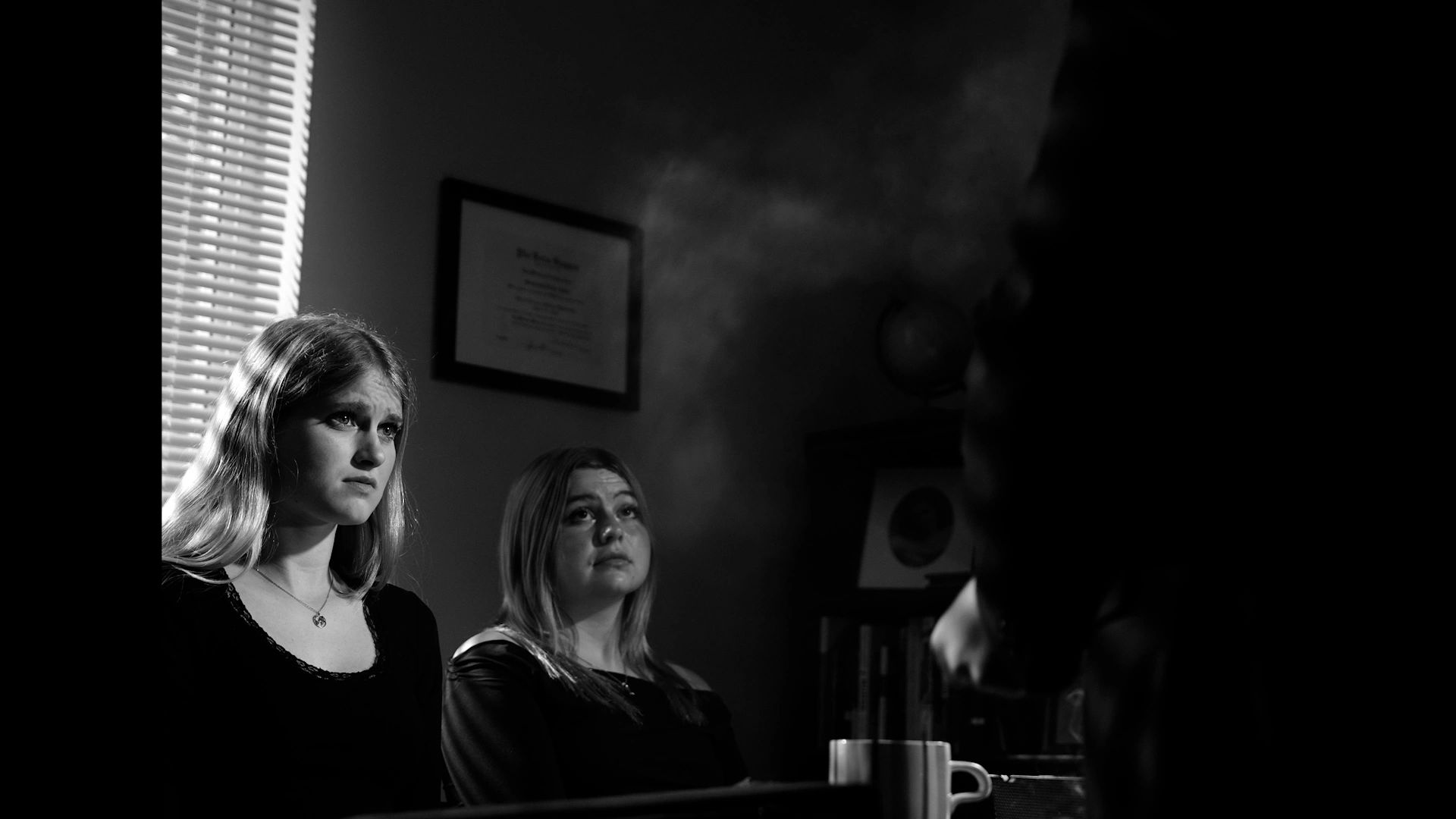 Two concerned women in a dimly lit room.