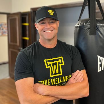 man in True Wellness t-shirt in fitness studio with punching bag