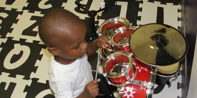 Young child playing a toy drum set.