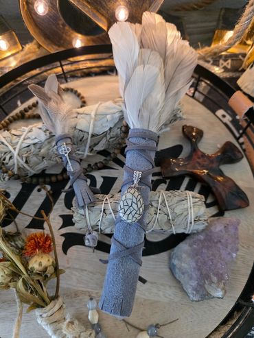 Decorative smudge sticks with feathers, crystals, and beads.