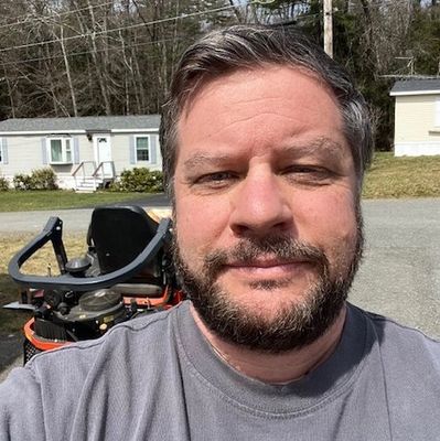 Man with beard taking a selfie outdoors.