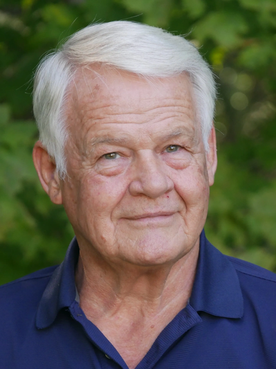 Portrait of an elderly man with white hair outdoors.