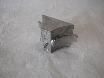 A small metallic geometric object on a white fabric.