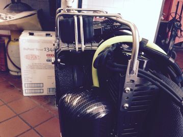 Close-up of a black wheeled suitcase with a box in the background.