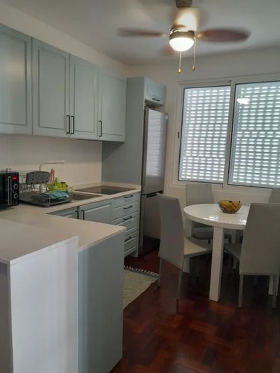 Modern kitchen with light blue cabinets and a small dining area.