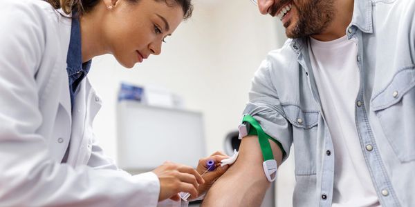 Photo of a tech drawing blood from the arm of a patient