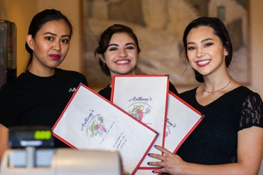Women smiling holding restaurant menu cards