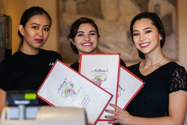 Women smiling holding restaurant menu cards