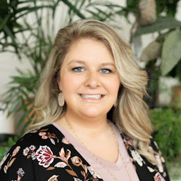 Smiling woman with blonde hair and floral cardigan.