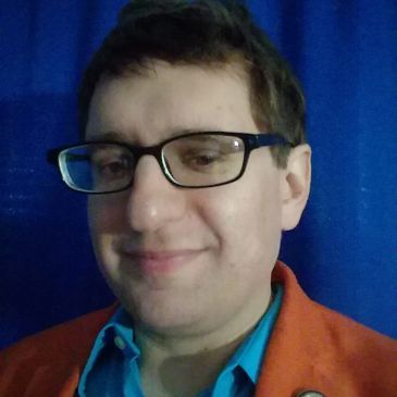 Man with glasses smiling against a blue background.
