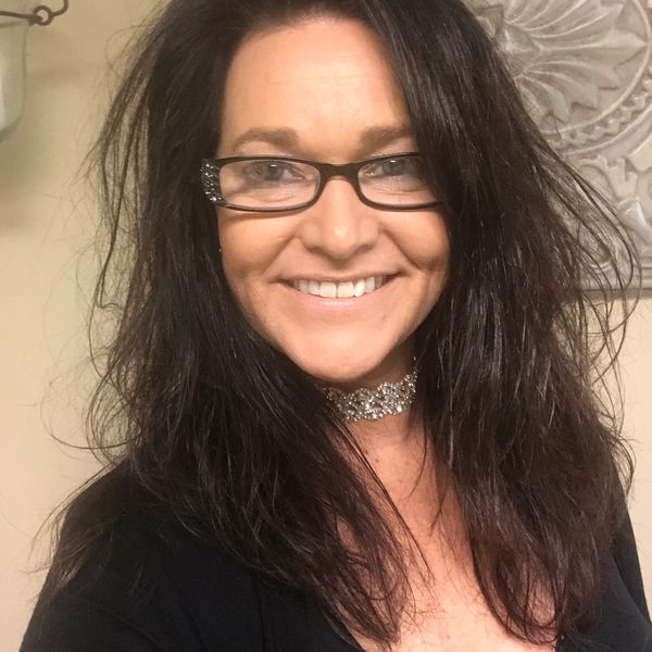 Smiling woman with glasses and a sparkly choker.