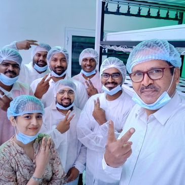 A group of people in protective hairnets and masks posing with peace signs.
