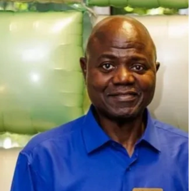 A man in a blue shirt smiling gently at the camera.