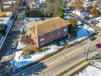 Aerial view of a brick building surrounded by snow and roads.