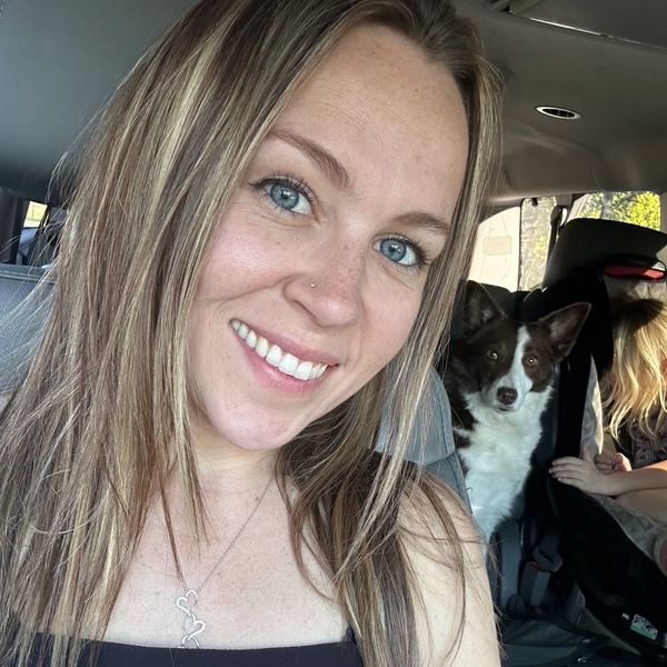 Smiling woman with blue eyes inside a car with a dog and a child.