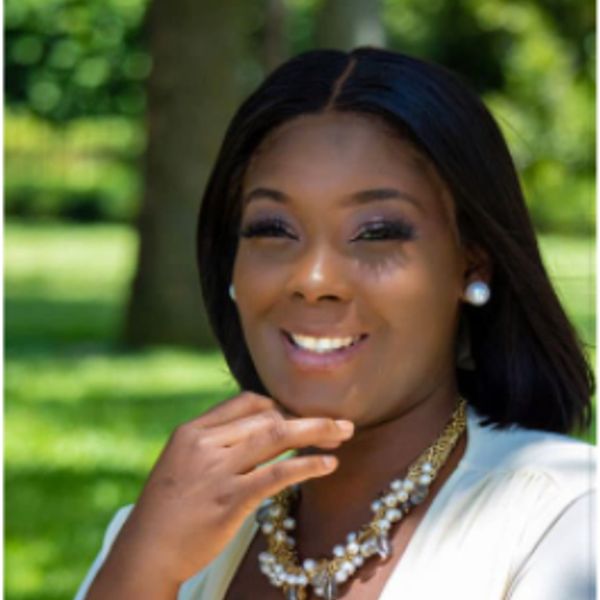Woman smiling outdoors with pearls and a necklace.