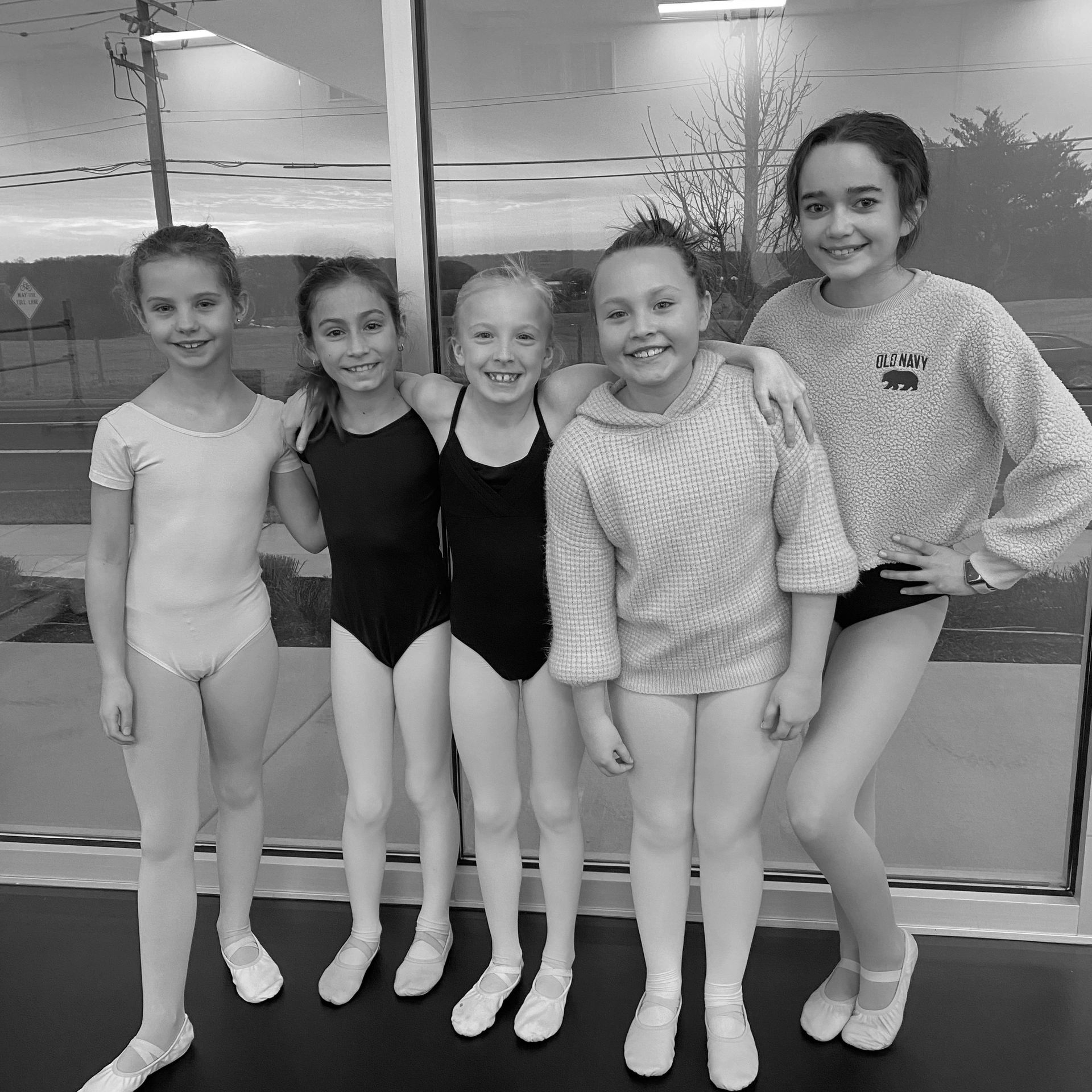 Group of five young ballet dancers smiling.