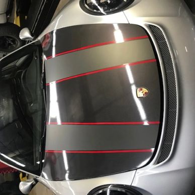 Porsche car hood with black and red racing stripes.