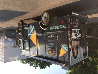 Black food truck with colorful geometric designs parked outdoors.