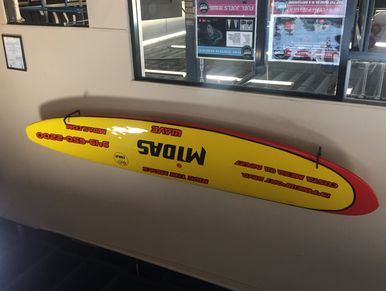 Yellow and red surfboard mounted on a wall indoors.