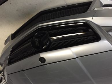 Close-up of a car's front grille and bumper in a parking garage.