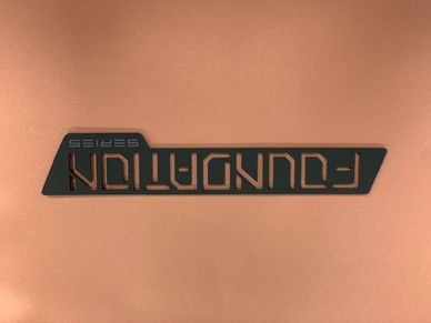 Logo for the FOUNDATION series on a copper surface.
