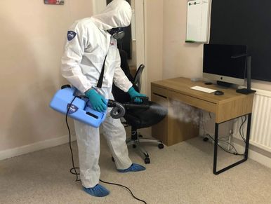 Person in protective suit fumigating a room.