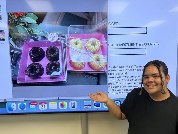 Person smiling and presenting a screen showing two boxes of assorted pastries.