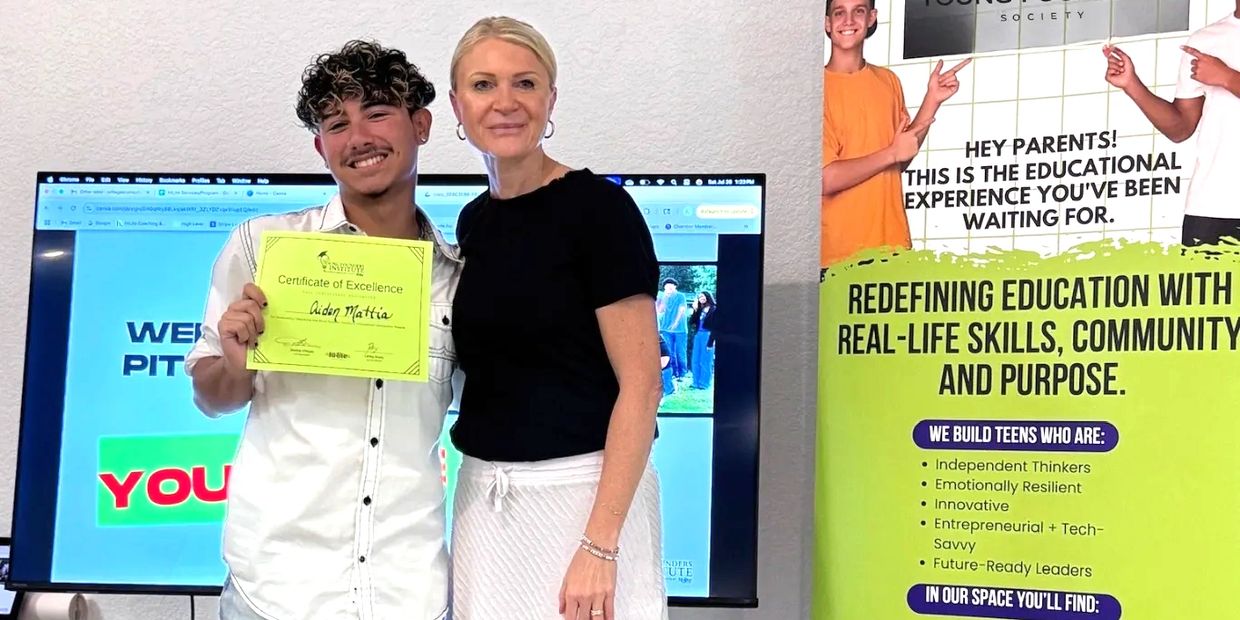 A young man proudly holds a Certificate of Excellence beside a smiling woman in an educational setting.