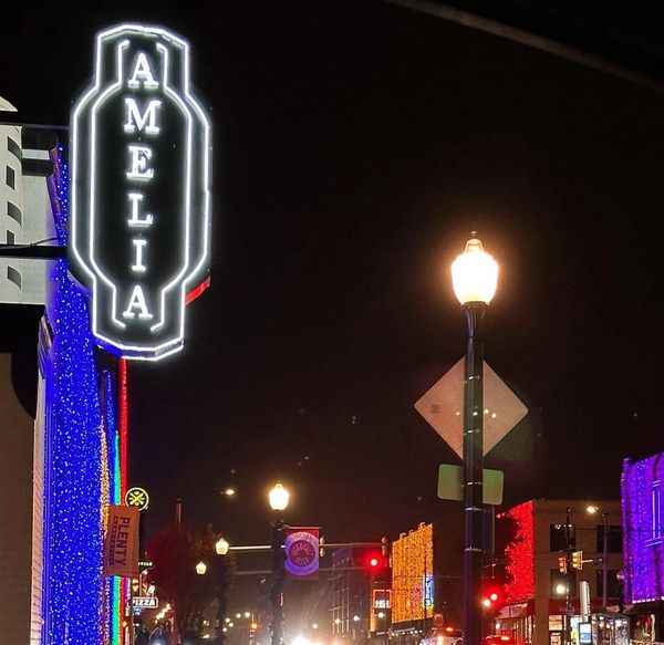 Night street scene with bright neon 'AMELIA' sign and colorful building lights.