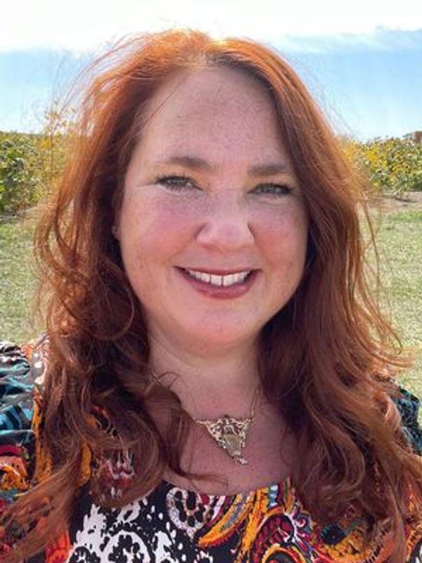 Nurse practitioner Jeanne-Marie Fournier. She has a kind smile, long, red hair, and is wearing color