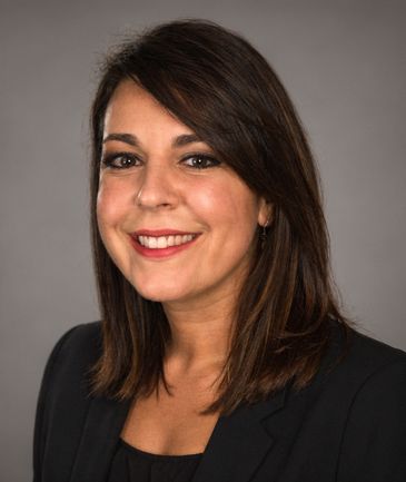 Smiling woman with shoulder-length brown hair in business attire.