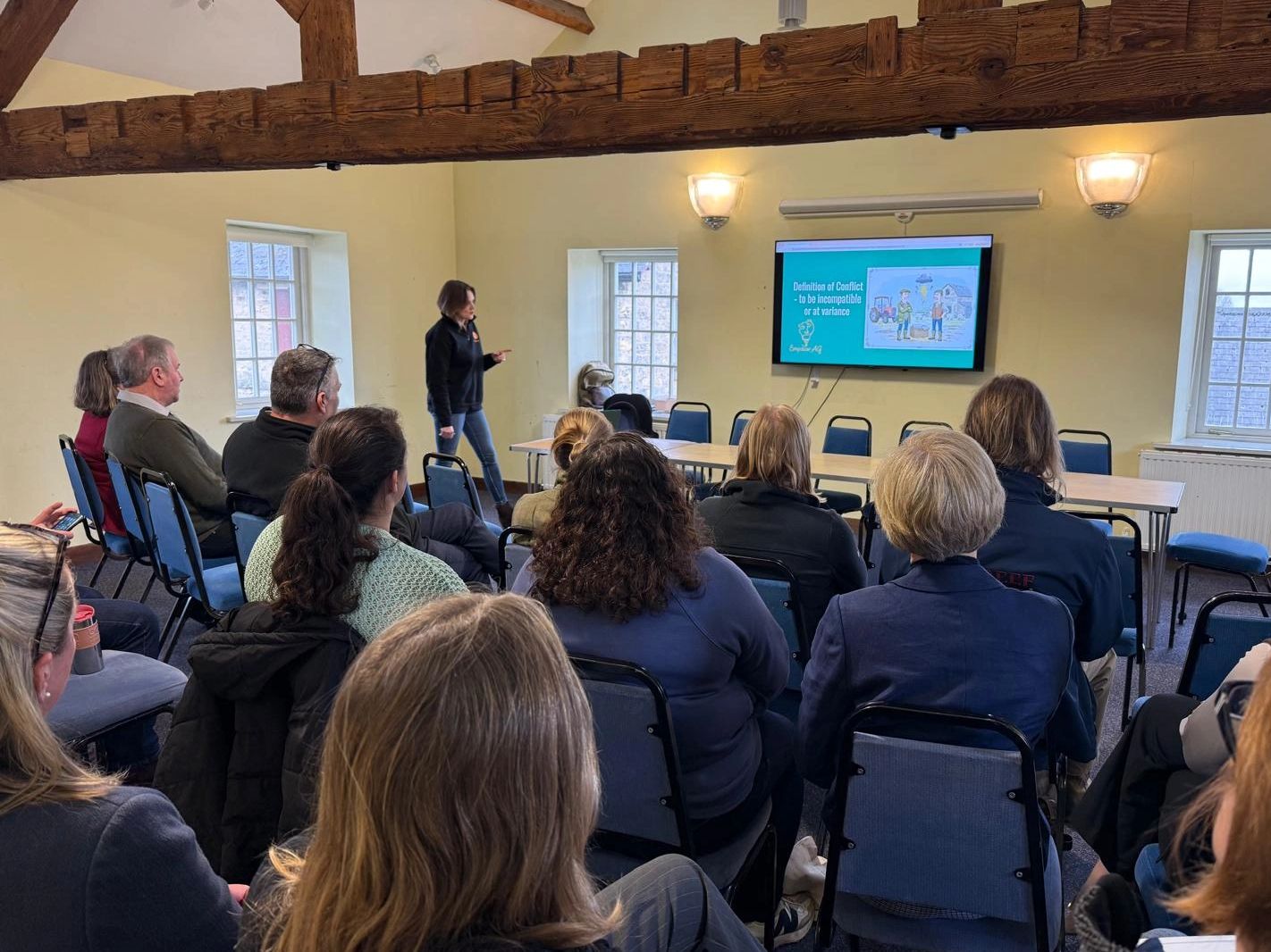 People attending a presentation on conflict definition in a cozy room.