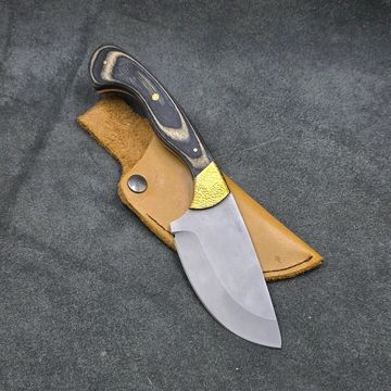 A fixed-blade knife with a wooden handle resting on a leather sheath.